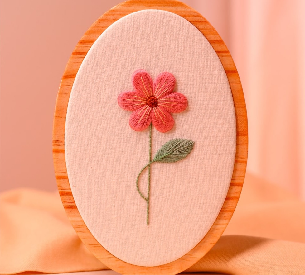 Flor rosa bordada em alto-relevo em bastidor de madeira